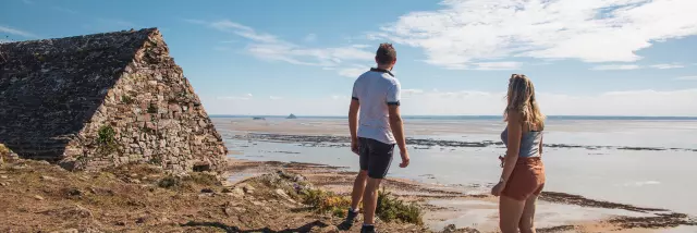 Un couple observe Tombelaine et le Mont saint-Michel depuis la cabane Vauban sur les falaises de Champeaux