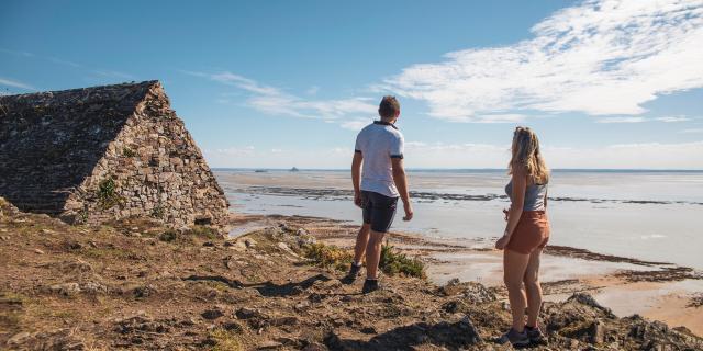 A couple observes Tombelaine and Mont saint-Michel from the Vauban hut on the Champeaux cliffs