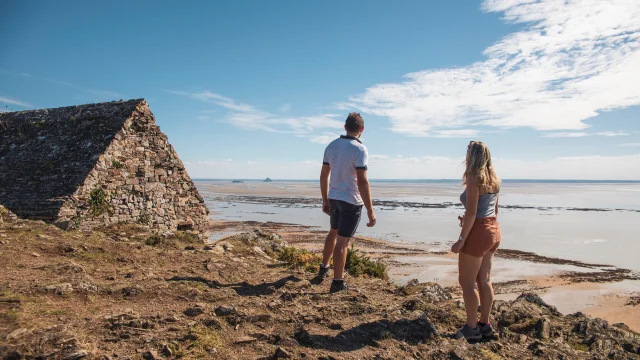 Ein Paar beobachtet Tombelaine und den Mont Saint-Michel von der Vauban-Hütte auf den Klippen von Champeaux aus.