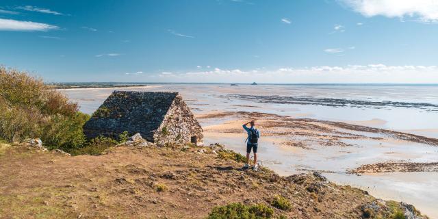 Ein Wanderer beobachtet die Bucht des Mont Saint-Michel von der Vauban-Hütte auf den Klippen von Champeaux aus.