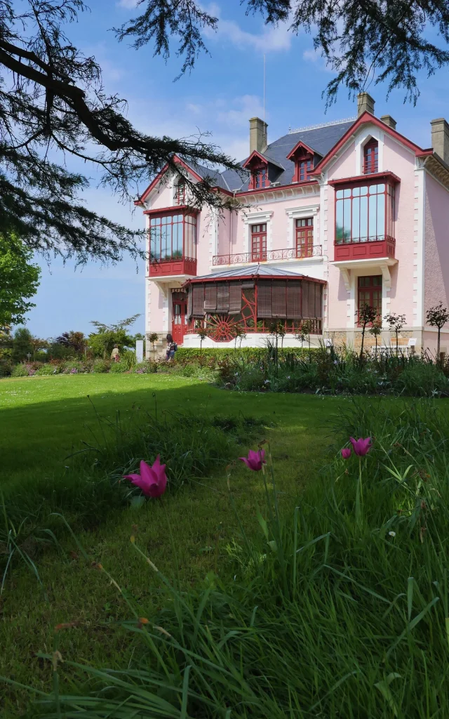 Entourés d'un magnifique jardin fleuri à flanc de falaise, la villa Les Rhumbs et ses murs roses abritent le musée Christian Dior à Granville