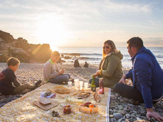 Une famille pique-nique sur les galets du port du Lude au coucher du soleil