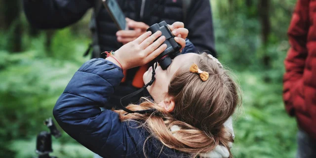 Petite fille qui regarde la nature à travers des jumelles