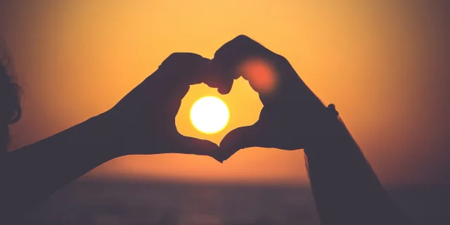 Cœur avec les mains face au coucher de soleil